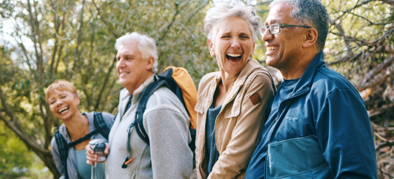 A group of older adults enjoys a refreshing outdoor hike, laughing and embracing the joys of staying active and social in nature.