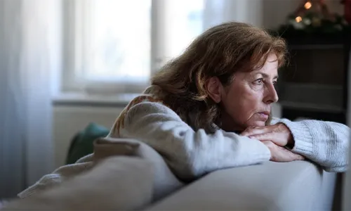 woman looking out the window over the back of the couch