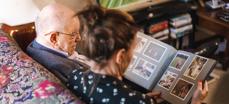 elderly man and younger woman looking at family photo album