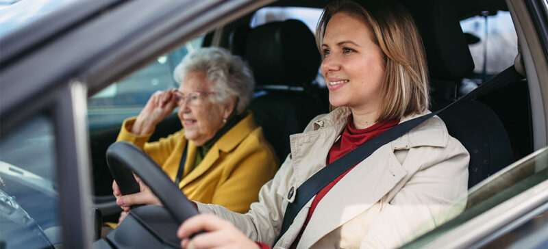 younger woman driving with elderly woman in passenger seat
