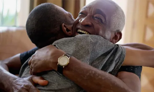older adult man hugging younger man and smiling