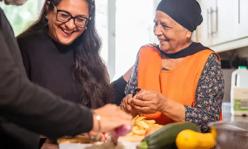 older adult woman with younger people in kitchen preparing healthy foods