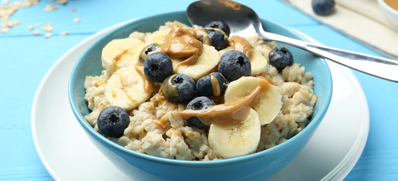 close up photo of bowl of oatmeal with fruit and peanut butter