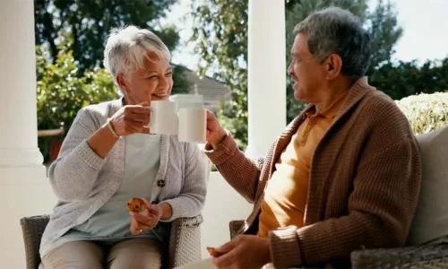 older adult women enjoying coffee seated outdoors on a porch
