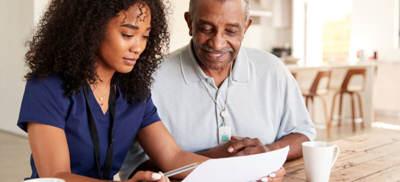 Older man and younger woman seated together looking over paperwork