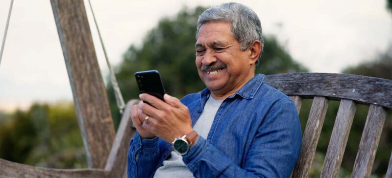 smiling older adult man looking at phone