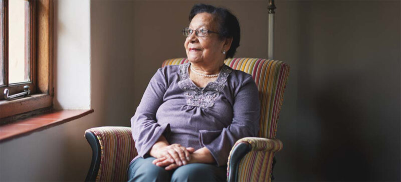 older adult woman seated by window