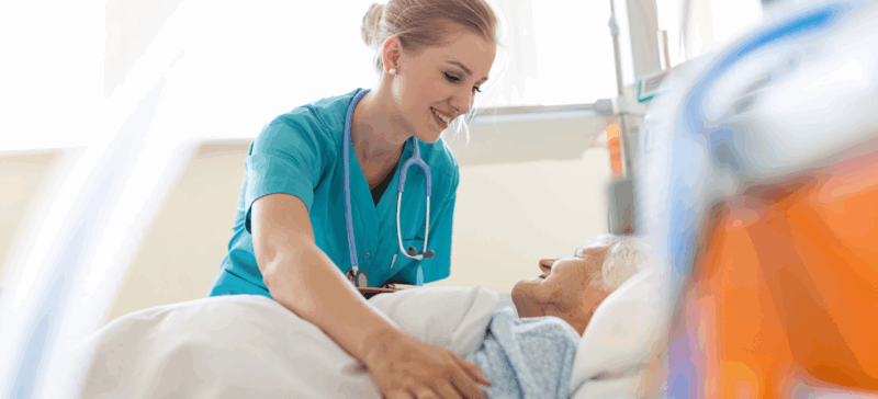 older adult patient in care setting with doctor or nurse providing care and smiling at patient