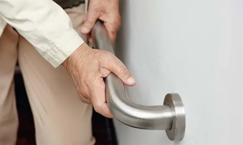 older adult person's hands utilizing a grab bar attached to a wall